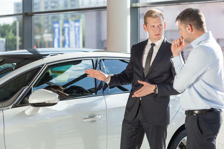 Car Salesman explaining the sweet deals of the car to the buyer