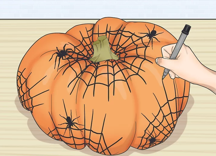Hand drawing spiders and web on a pumpkin with a black marker