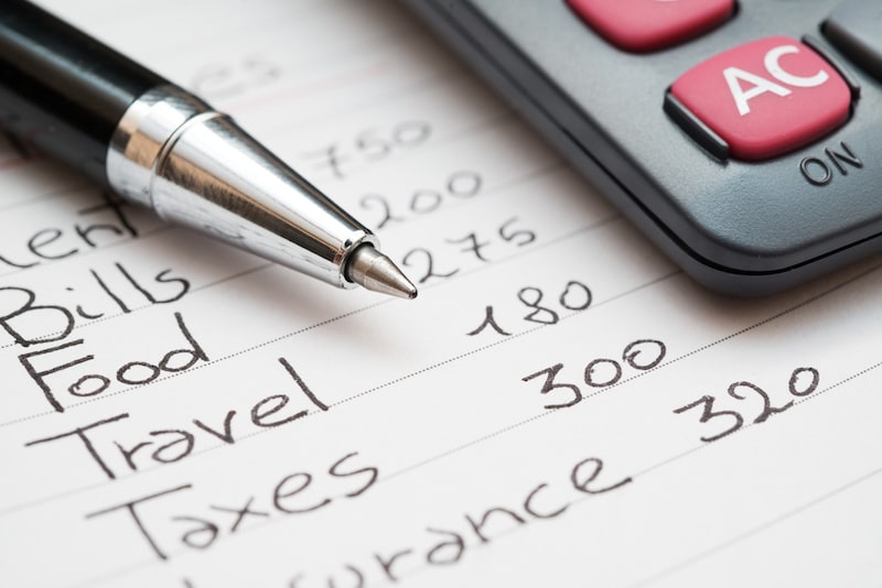 List of monthly expenses in a paper with pen & calculator