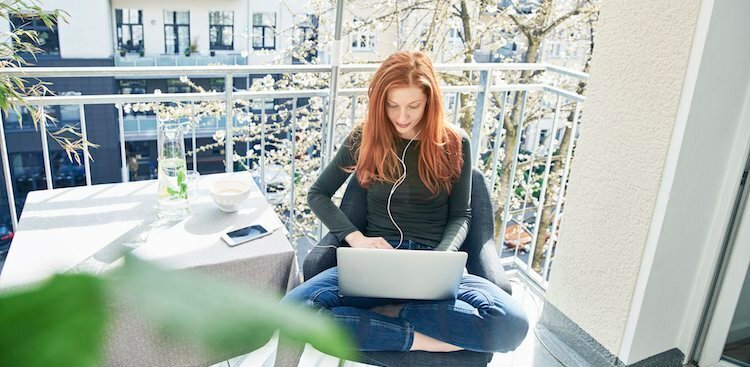 Redhead woman cross-legged creating a resume in laptop