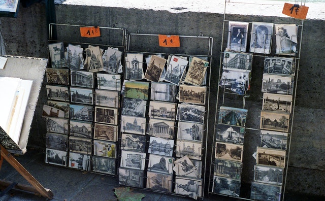 Black and white and colored postcards stacked on a rack and sold on a sidewalk for 1 euro each