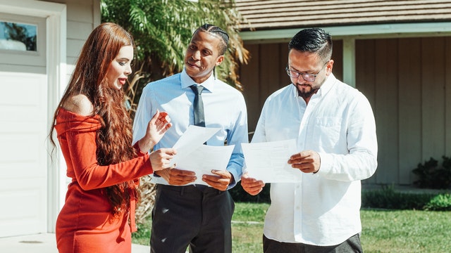 Male and female homebuyers read real estate contract as real estate agent looks on
