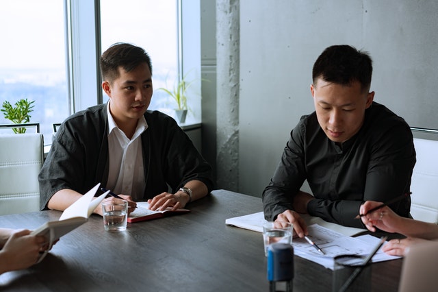 Two male Asian Pacific Americans discuss their business plan to potential investors