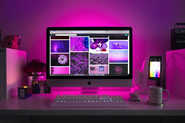 Silver iMac desktop displays a collage of graphic designs on its monitor