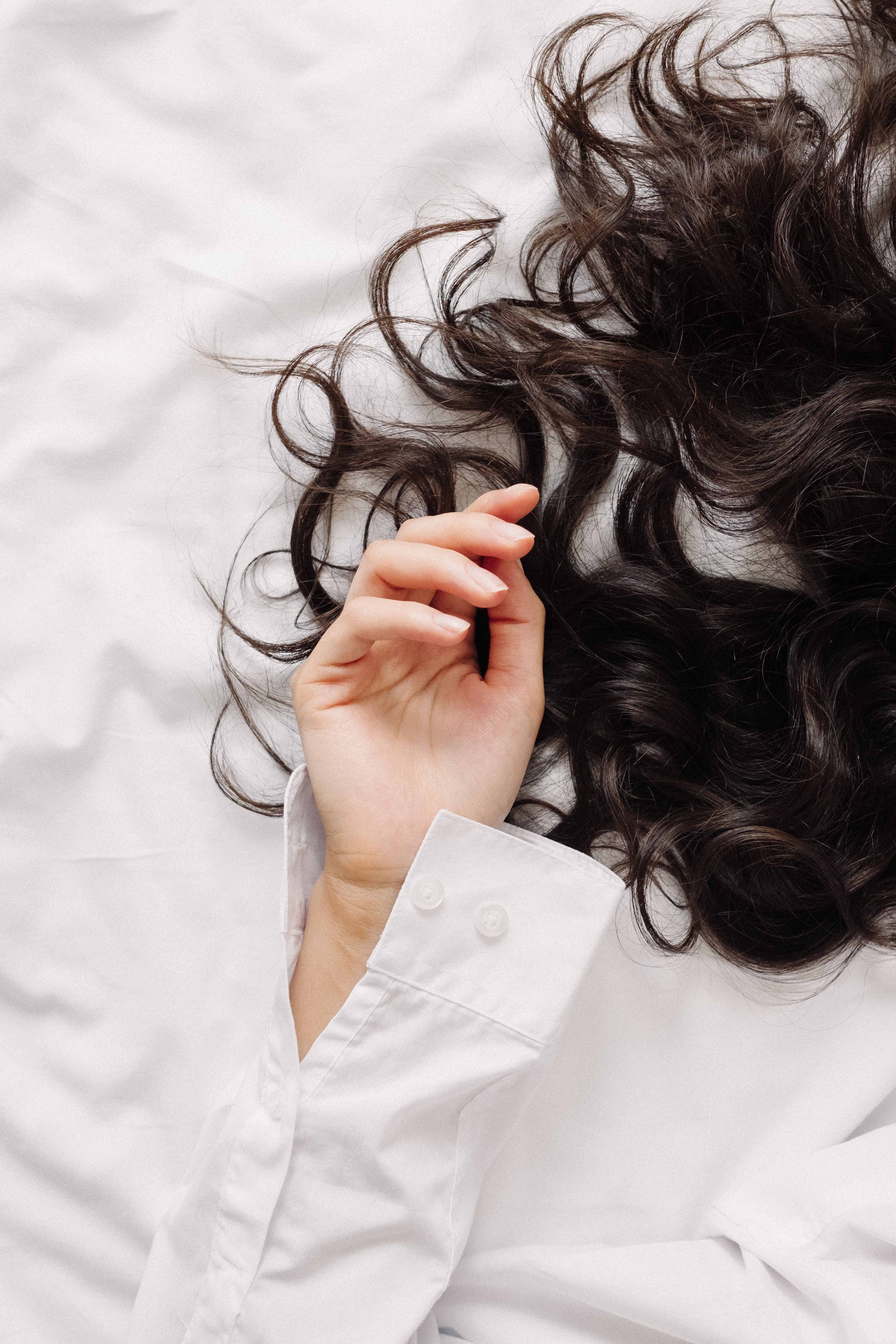 A Half Of a Woman Body Showing Her Hand And Her Hair In A bed