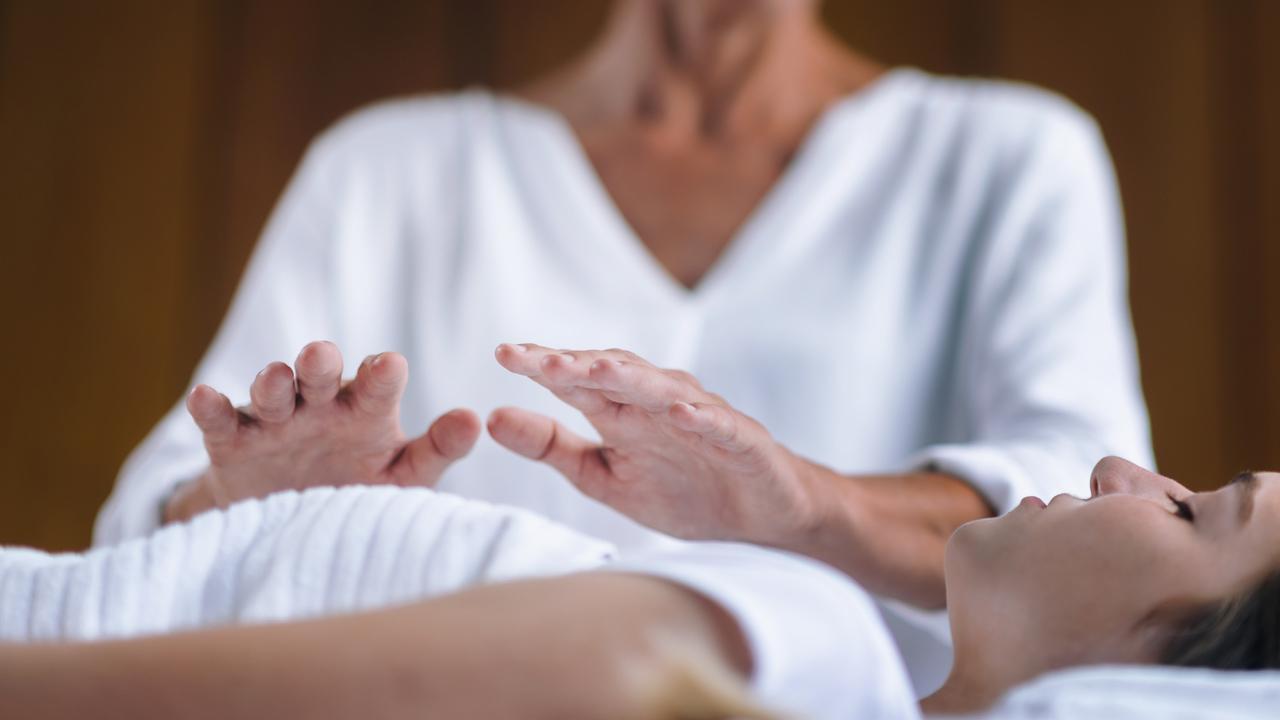Old woman practicing reiki in a young woman